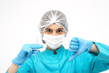Fototapeta na wymiar Medical worker in protective clothing,gloves and mask holding a syringe and showing the thumb down sign.Medicine and healthcare concept.Coronavirus vaccination concept.