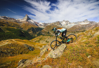 Fototapeta na wymiar Women on a mountainbike drives down the wallis mountains for the matterhorn in the swiss alps