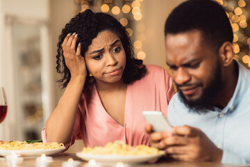 Unhappy Black Woman Bored On Date, Man Using Phone