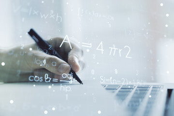 Creative scientific formula hologram with hand writing in notepad on background with laptop,...