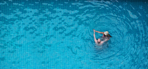 People swimming in pool. In summer sunny day swimming pool blue color clear water and people enjoying and top view angle. People relaxing in summer hot day in hotel pool and bird eye view angle