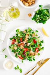 Caesar salad with grilled chicken meat, fresh tomato, croutons, lambs lettuce and parmesan cheese. Healthy lunch. Top view