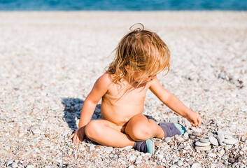 Toddler girl playing with pebbles on beach
