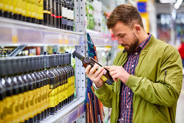 customer male reading wine composition in supermarket, want to buy some alochol for holidays