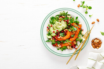 Fresh vegetable salad with lambs lettuce, baked butternut squash or pumpkin, avocado, pomegranate, cashew and almond nuts. Healthy vegetarian food concept. Top view