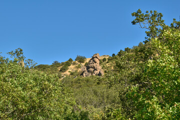A pile of stones of unusual shape on the slope of a green hill
