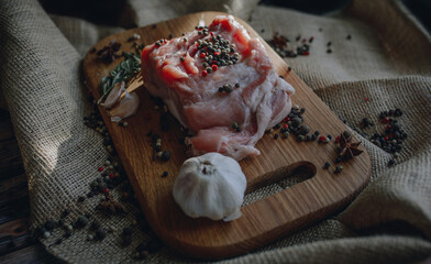 Uncooked piece of fresh meat with peppercorn and garlic on the wooden cuttig board and burlap 