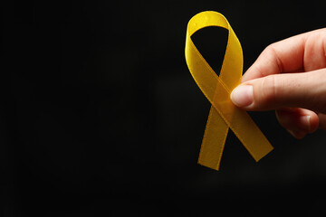 Woman hand with gold ribbon on dark background