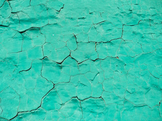 Obraz premium Close-up old green cracked paint. The texture of the old emerald paint with cracks. Dried in the sun and cracked color on the wall of country house. Peeling coating.