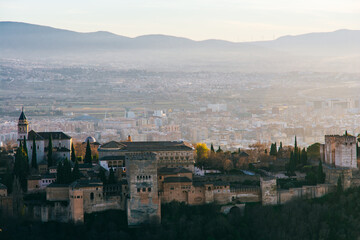 Alhambra palace in Granada at sunset from San Miguel lookout with some fog in the background