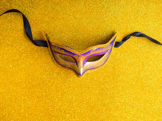 Carnival mardi gras party purple mask on golden background with decor.