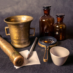 Vintage glass bottles and magnifying glass on black background, close up