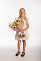 Studio portrait of cute blonde girl in white dress with wooden basket of flowers, white background, selective focus