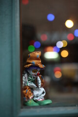 Fototapeta na wymiar unhappy clown toy close up shooting. bokeh background. in front of window clown toy sad in the night
