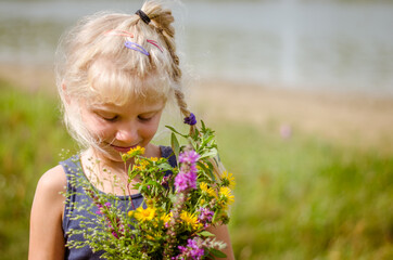 cute child  with huge colorful bunch of wild flowers