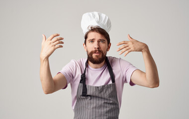 a professional chef in a headdress and an apron gestures with his hands