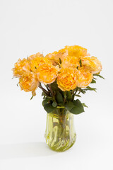 The bouquet of orange roses are in the vase of old green glass on white background.