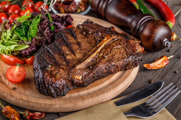 Beef T-Bone steak, herbs and spices on a dark table. Top view. Free space for your text.