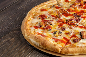 Fresh pizza with tomato sauce, black olives, mozzarella cheese, ham on wooden table closeup. Space for text or copy space. Pizza menu. Restaurant menu advertise