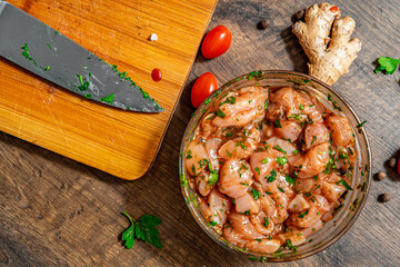 Raw diet marinated chicken meat with garlic, ginger and teriyaki sauce in a glass bowl on wooden...
