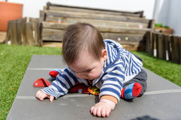 Simpática bebé jugando sentada en el cesped en jardin de casa