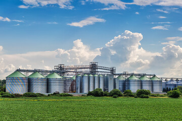 Agricultural Silos. Storage and drying of grains, wheat, corn, soy, sunflower against the blue sky with white clouds.Storage of the crop