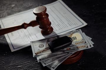 Car keys on dollar banknotes and wooden judge gavel close-up.