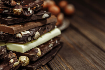 Stack of chocolate slices with mint leaf on a wooden table.Assortment of fine chocolates in white, dark, and milk chocolate. Sweet food photo concept.
