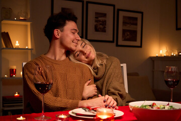 Happy young couple in love hugging, drinking wine, enjoying tender moment together celebrating...