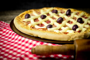 Pizza - tradicional brasileira, vegetais, ingredientes em um fundo escuro de madeira envelhecida. Espaço para texto.