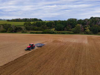 Farmer with tractor on wide field tilling the soil