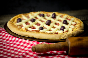 Pizza - tradicional brasileira, vegetais, ingredientes em um fundo escuro de madeira envelhecida....