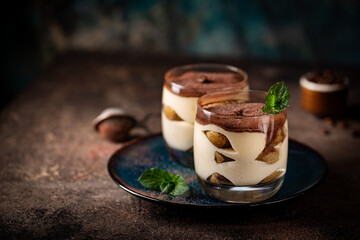 Traditional Italian dessert tiramisu in a glass on on dark background