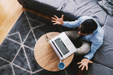 Top view of attractive programmer dressed business casual sitting on the floor in his living room...