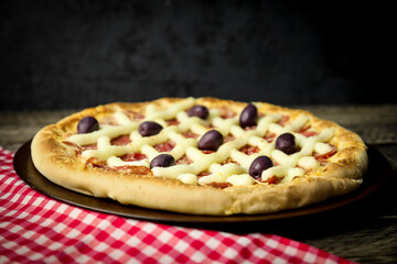 Pizza - tradicional brasileira, vegetais, ingredientes em um fundo escuro de madeira envelhecida. Espaço para texto.