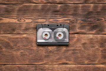Old retro cassette on the brown wooden table background.