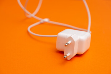 the charger is on an orange background. The charger is designed to charge a mobile phone or tablet