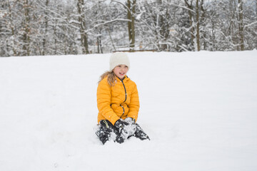 Fototapeta na wymiar Young happy girl is playing with snow in winter. Outdoor activity and fun in white winter nature.