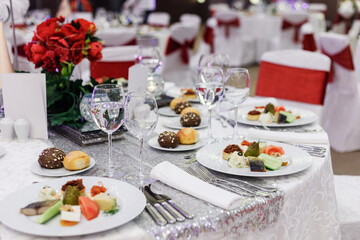 Festive round table setting in a prestigious restaurant for dinner. Banquet decoration with white and red
