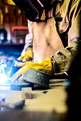 Obraz premium Elderly man welding in a workshop surrounded by tools