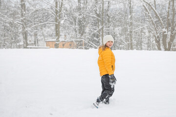 Young happy girl is walking in snow in winter. Outdoor activity and fun in winter nature.