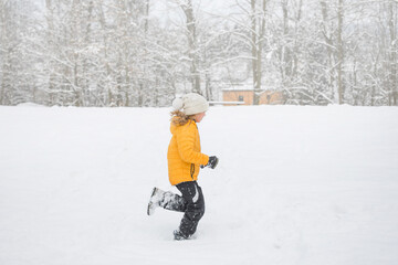 Fototapeta na wymiar Young happy girl is running in snow in winter. Outdoor activity and fun in winter nature.