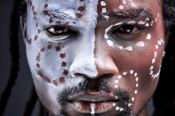 afro man eyes looking at camera, confident gaze, primitive guy with paintings on face. portrait