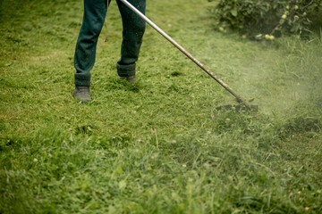 The head of a gasoline manual lawnmower while working against the background of freshly mown grass.