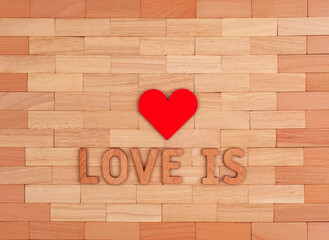 The inscription love is and a red heart on a wooden background of small pieces.