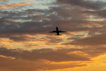 夕焼けの中を上昇していく航空機