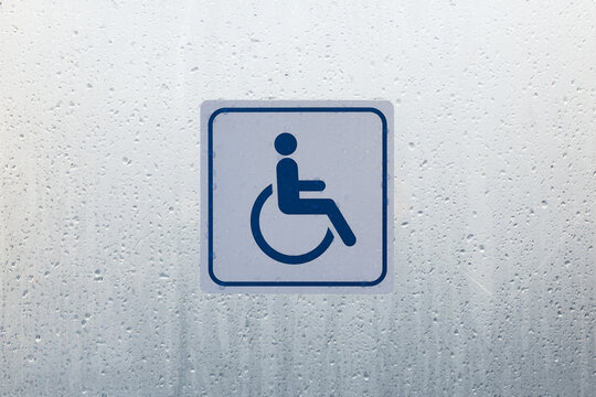 Symbol of wheelchair users on the wet glass.