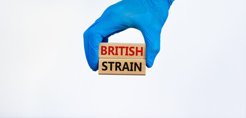 Covid-19 british strain symbol. Hand in blue glove holds wooden blocks, words 'british strain'. Beautiful white background. Copy space. Medical and COVID-19 british strain virus concept.