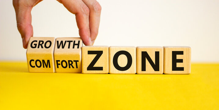 Comfort or growth zone symbol. Hand turns wooden cubes and changes words 'comfort zone' to 'growth zone'. Beautiful yellow table, white background, copy space. Business, psychology concept.