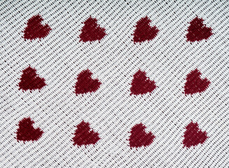 Knitted white background with a red pattern in the shape of heart.